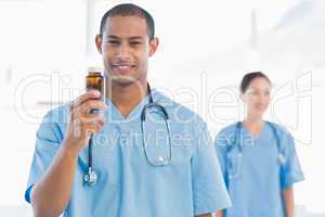 Smiling doctor holding a bottle of pills with colleague