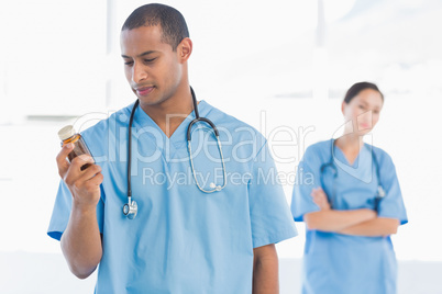 Doctor holding a bottle of pills with colleague in background