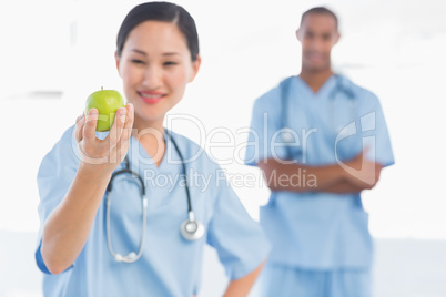 Female surgeon holding an apple with colleague in hospital