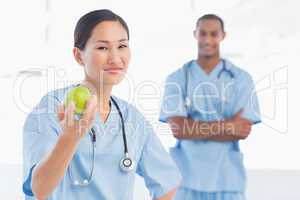 Smiling surgeon holding an apple with colleague in hospital