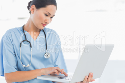 Concentrated surgeon using a laptop in hospital