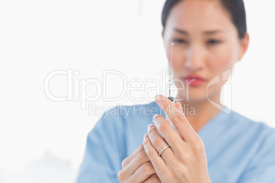 Serious female doctor holding an injection