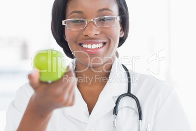 Portrait of a smiling female doctor holding an apple