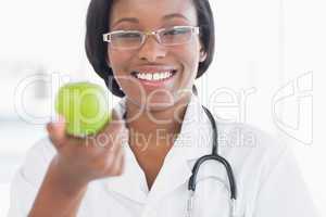 Portrait of a smiling female doctor holding an apple