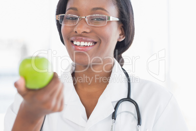 Portrait of a smiling female doctor holding an apple