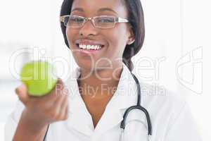 Portrait of a smiling female doctor holding an apple