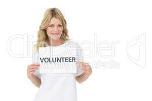 Portrait of a smiling young female volunteer holding placard