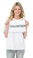 Portrait of a smiling young female volunteer holding placard