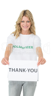 Smiling young female volunteer holding 'thank you' paper