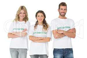 Portrait of three happy volunteers standing with hands crossed