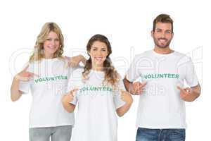 Portrait of three happy volunteers pointing to themselves