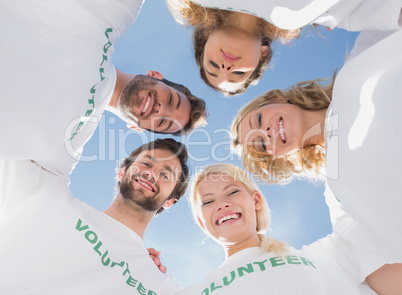 Happy volunteers forming a huddle against blue sky