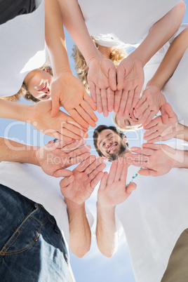 Happy volunteers with hands together against blue sky