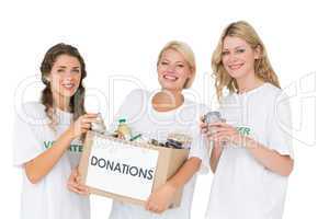 Portrait of three smiling young women with donation box