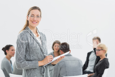 Portrait of therapist with group therapy in session in backgroun