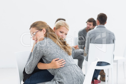 Group therapy session with therapist and client hugging