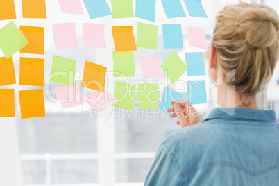 Rear view of a female artist looking at colorful sticky notes