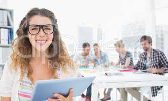 Smiling woman using digital tablet with colleagues in background