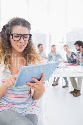 Woman using digital tablet with colleagues in background
