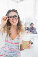 Woman holding disposable coffee cup with colleagues in backgroun