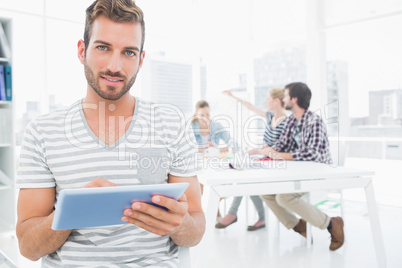 Man using digital tablet with colleagues in background
