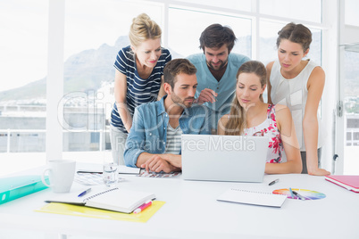 Casual business people using laptop together