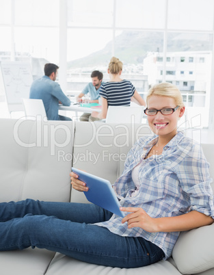 Woman using digital tablet with colleagues in background at crea