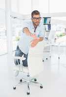 Happy young man kneeling on chair in office