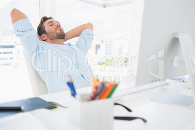 Casual man resting with hands behind head in office