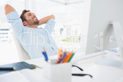 Casual young man resting with hands behind head in office