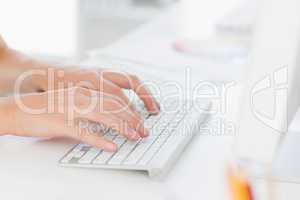 Close-up of hands using computer keyboard in office