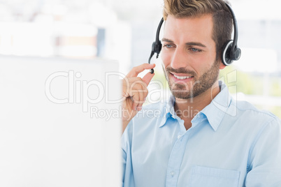 Close-up of a casual young man with headset using computer