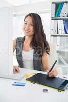 Smiling casual female photo editor using graphics tablet