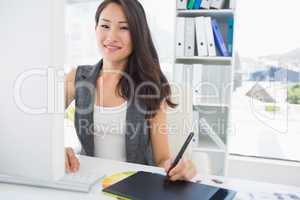 Smiling casual female photo editor using graphics tablet