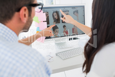 Rear view of casual photo editors working on computer