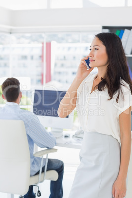 Female artist using mobile phone with colleague in the backgroun