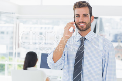 Male artist using mobile phone with colleague in background