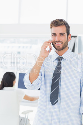 Male artist using mobile phone with colleague in background