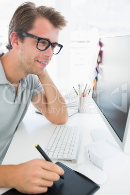 Side view of a casual male photo editor using graphics tablet