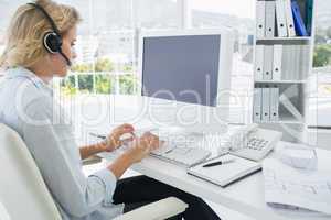 Casual young woman with headset using computer