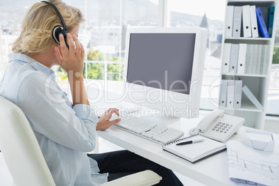 Casual young woman with headset using computer