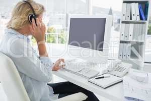 Casual young woman with headset using computer