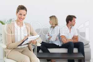 Financial adviser writing notes with couple in background