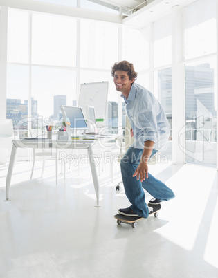 Happy man skateboarding in a bright office