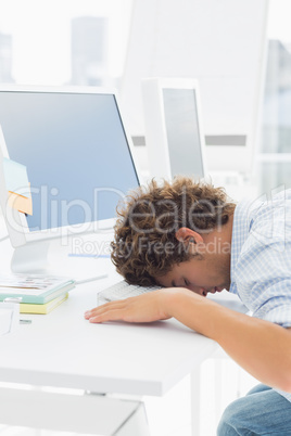 Casual businessman with head over keyboard at desk