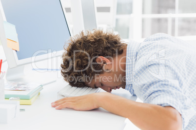 Casual businessman with head over keyboard at desk