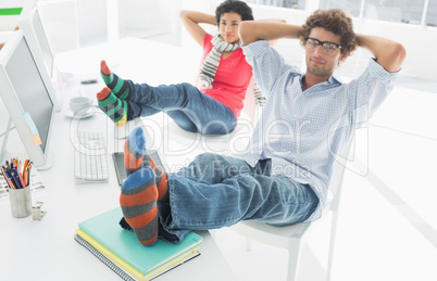 Relaxed casual couple with legs on desk in office