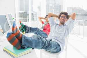 Relaxed casual couple with legs on desk in office