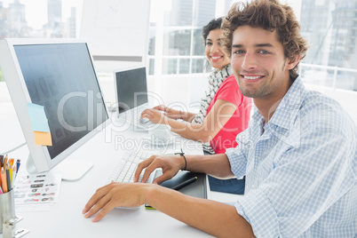 Casual couple using computers in office