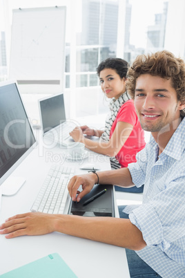 Casual couple using computers in office